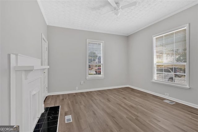 unfurnished living room with a wealth of natural light, visible vents, a textured ceiling, and wood finished floors