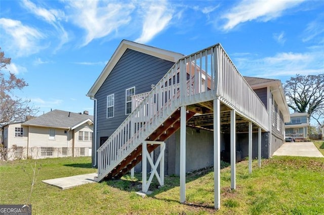 rear view of house featuring stairway, a wooden deck, and a yard