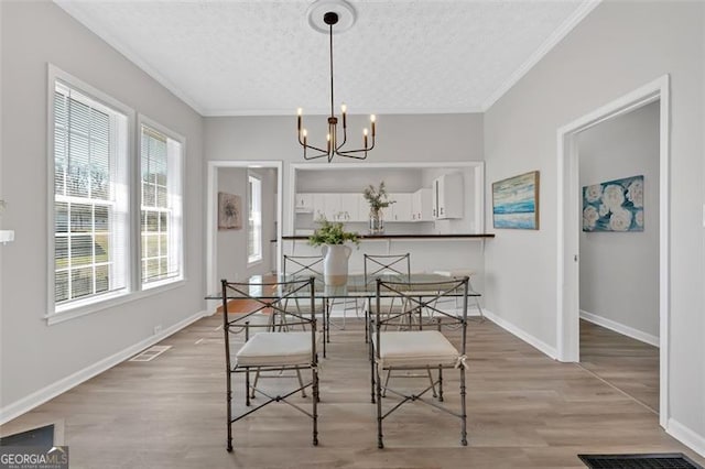 dining space with visible vents, light wood-style flooring, a textured ceiling, and crown molding