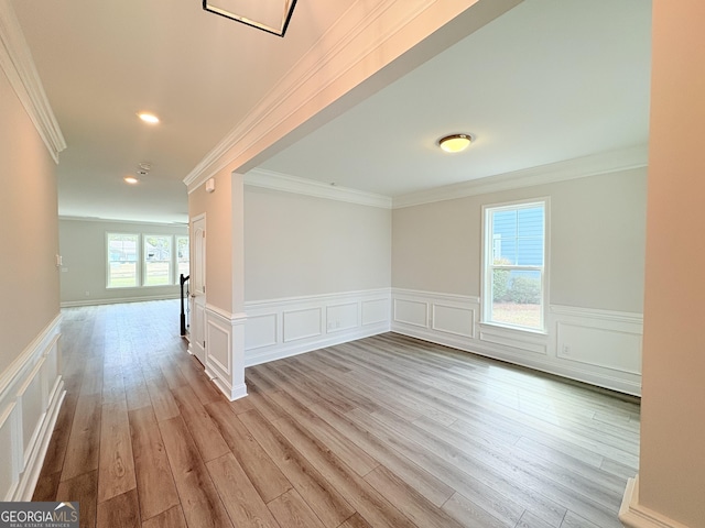 unfurnished room featuring light wood-style flooring, a wainscoted wall, and ornamental molding