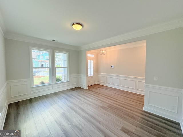 unfurnished room featuring visible vents, ornamental molding, and wood finished floors