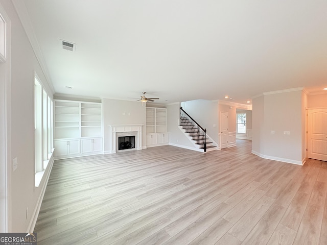 unfurnished living room featuring visible vents, crown molding, stairway, a fireplace, and light wood-style floors