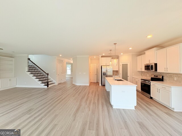 kitchen featuring a sink, stainless steel appliances, open floor plan, and ornamental molding