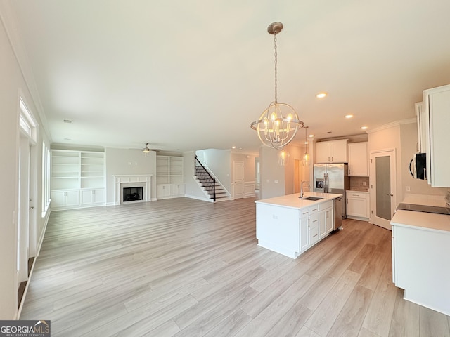 kitchen featuring light wood-style flooring, a sink, appliances with stainless steel finishes, a fireplace, and light countertops