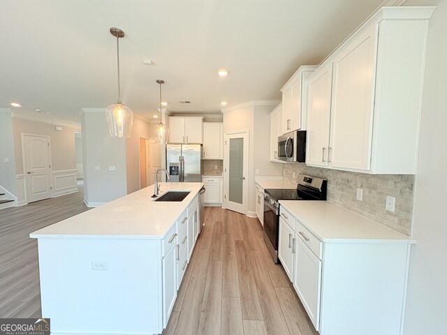 kitchen with backsplash, a center island with sink, appliances with stainless steel finishes, white cabinets, and a sink