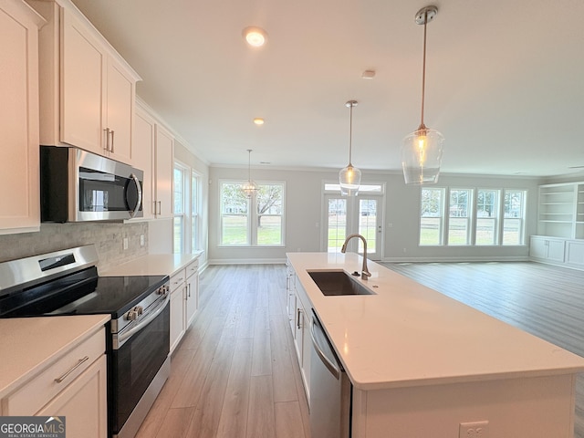 kitchen featuring open floor plan, ornamental molding, decorative backsplash, stainless steel appliances, and a sink