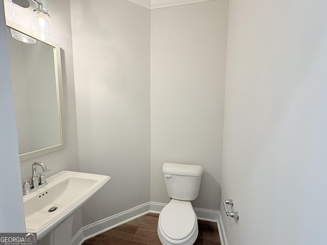 bathroom featuring wood finished floors, toilet, baseboards, and a sink