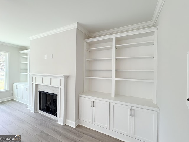 unfurnished living room with a fireplace, baseboards, crown molding, and light wood-style floors