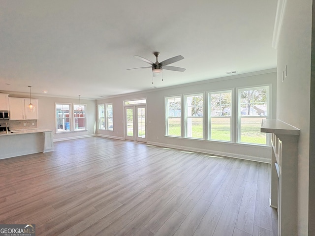 unfurnished living room featuring light wood finished floors, a ceiling fan, crown molding, and baseboards