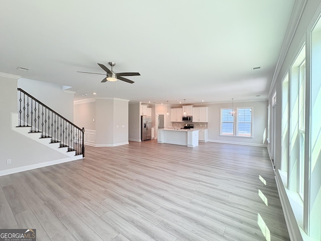 unfurnished living room with light wood-type flooring, visible vents, ornamental molding, baseboards, and stairs