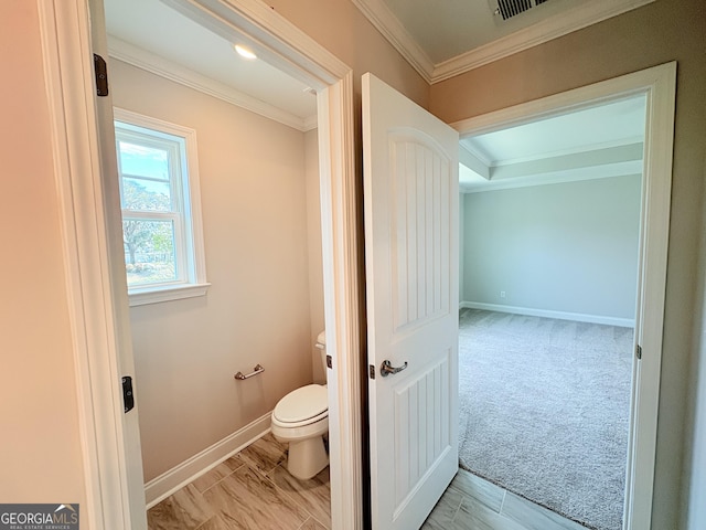 bathroom featuring crown molding, toilet, and baseboards