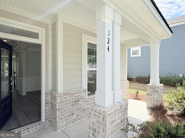 view of exterior entry featuring brick siding and covered porch