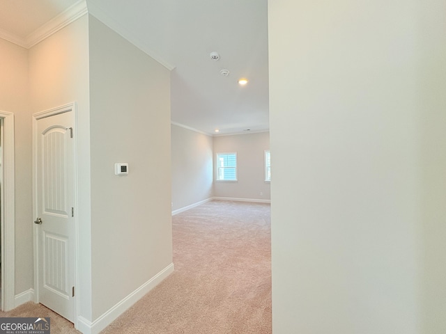 hallway featuring light colored carpet, crown molding, and baseboards