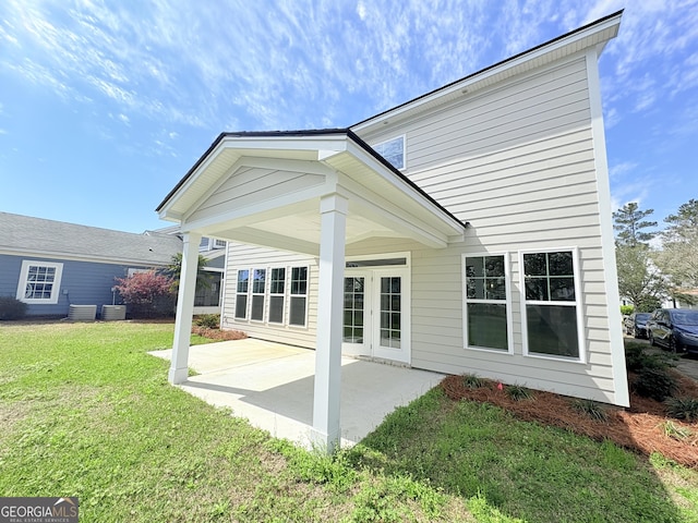 back of property with central AC unit, a patio, and a yard