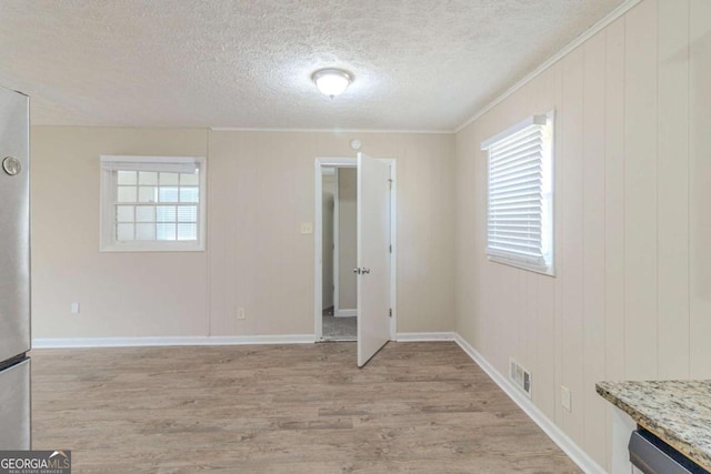 interior space with visible vents, baseboards, a textured ceiling, and light wood-style flooring