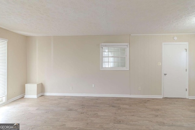 unfurnished room with baseboards, light wood-type flooring, and a textured ceiling