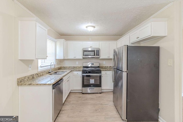 kitchen featuring a sink, light wood-style flooring, white cabinetry, and stainless steel appliances