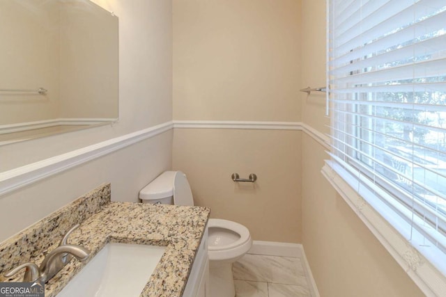 half bath featuring toilet, vanity, and baseboards