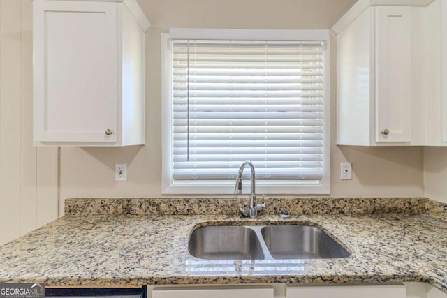 kitchen featuring a sink, light stone countertops, and white cabinets