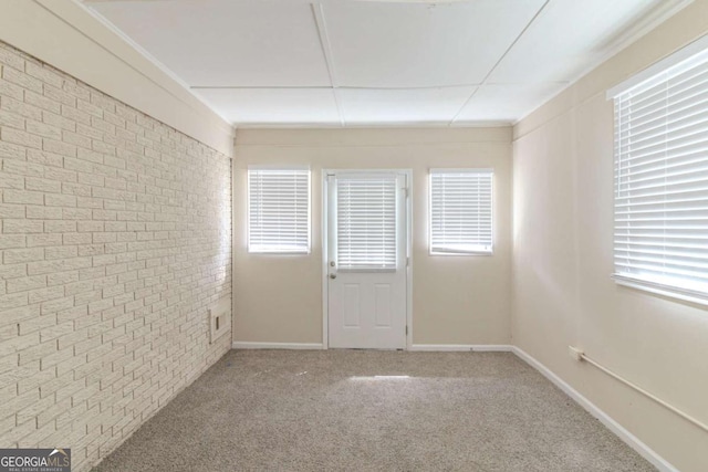 spare room with baseboards, carpet floors, and brick wall