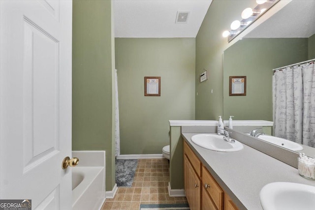 bathroom featuring double vanity, toilet, baseboards, and a sink