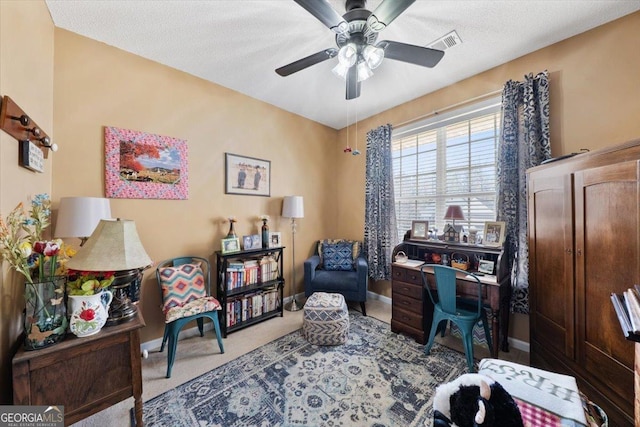 office featuring baseboards, visible vents, carpet floors, ceiling fan, and a textured ceiling