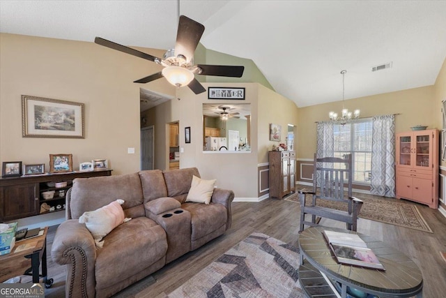 living area featuring visible vents, baseboards, lofted ceiling, ceiling fan with notable chandelier, and wood finished floors