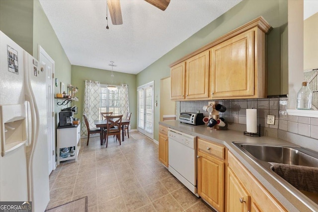 kitchen featuring backsplash, light brown cabinets, baseboards, white appliances, and a sink