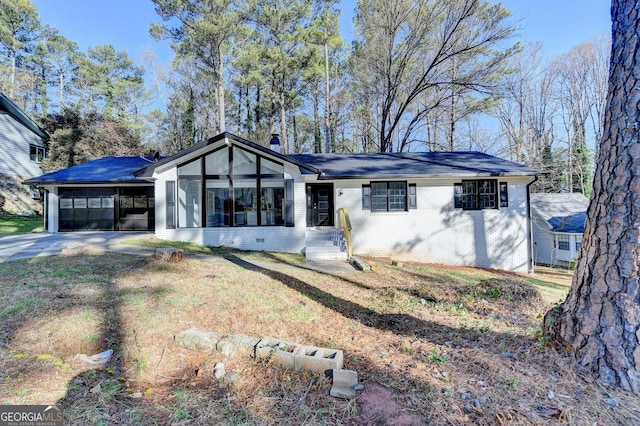 view of front of property featuring concrete driveway, a front yard, a sunroom, crawl space, and brick siding