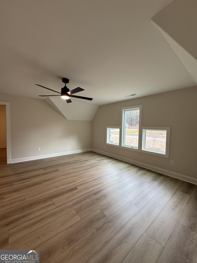 additional living space with vaulted ceiling, visible vents, baseboards, and wood finished floors