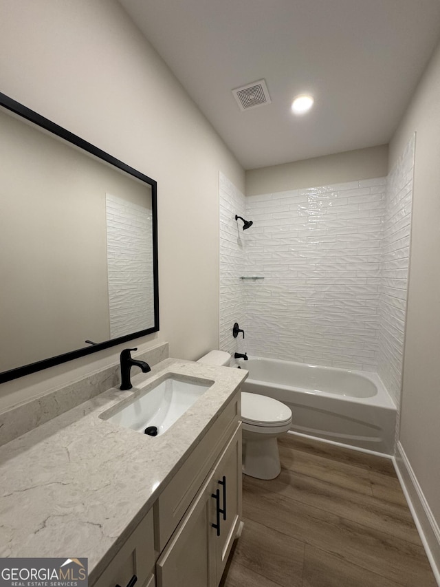 bathroom featuring vanity, wood finished floors, visible vents, bathtub / shower combination, and toilet