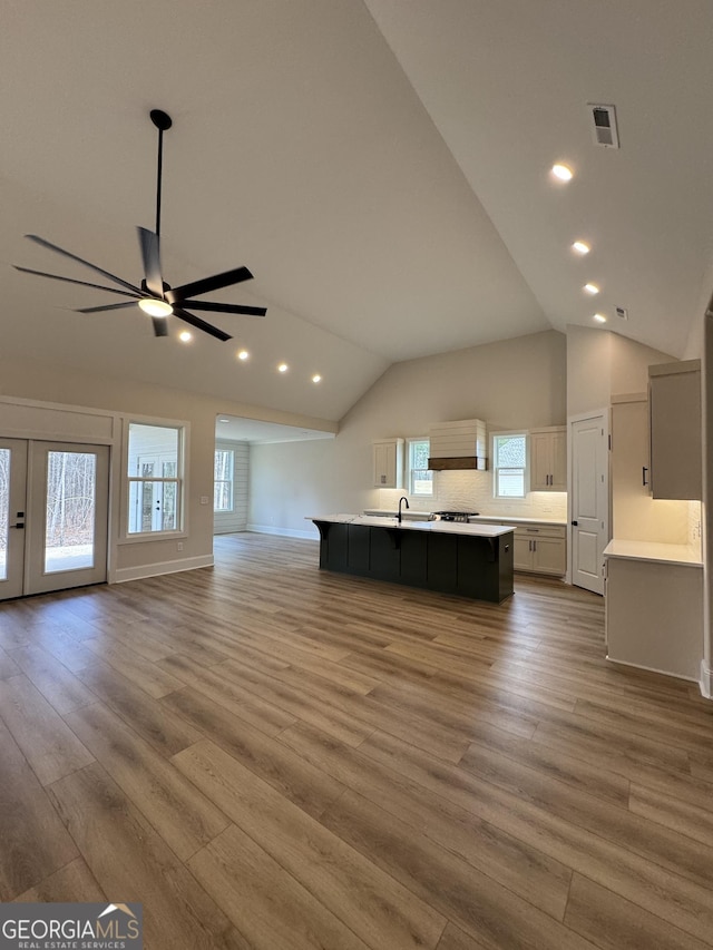 unfurnished living room with visible vents, wood finished floors, ceiling fan, and a sink