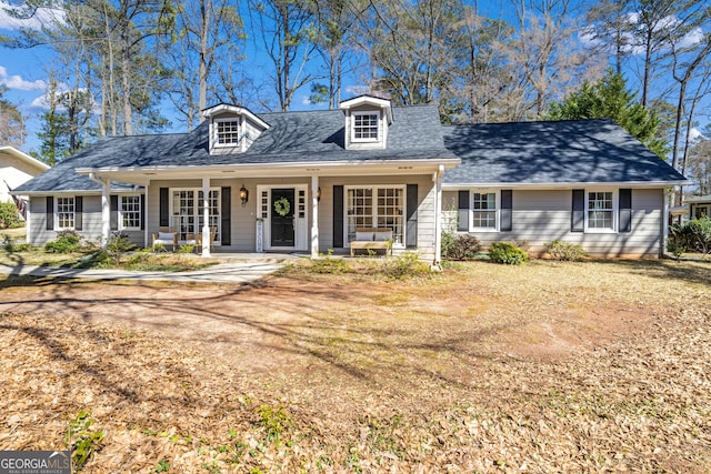 new england style home featuring a porch and a shingled roof