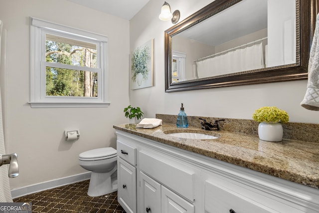 bathroom featuring vanity, toilet, and baseboards