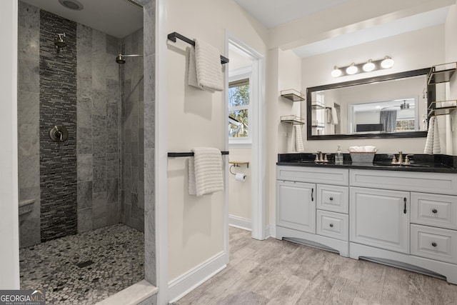 full bath with wood finished floors, a walk in shower, double vanity, and a sink