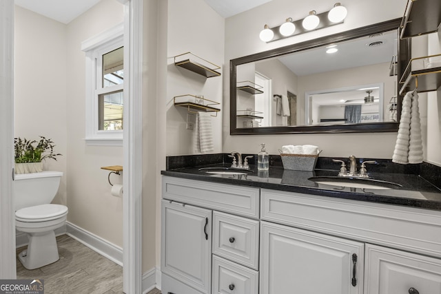 bathroom with double vanity, wood finished floors, toilet, and a sink