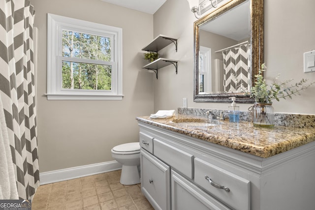 full bathroom with baseboards, toilet, and vanity