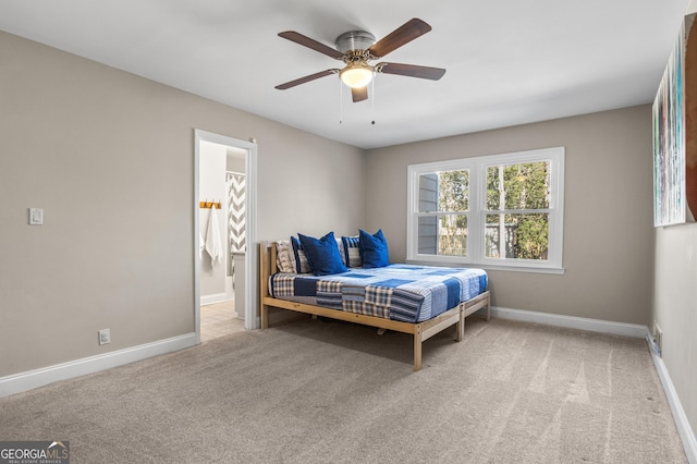 carpeted bedroom with ensuite bath, baseboards, and a ceiling fan