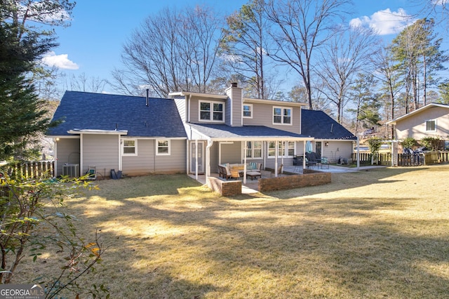 back of property with a patio area, a chimney, a yard, and fence