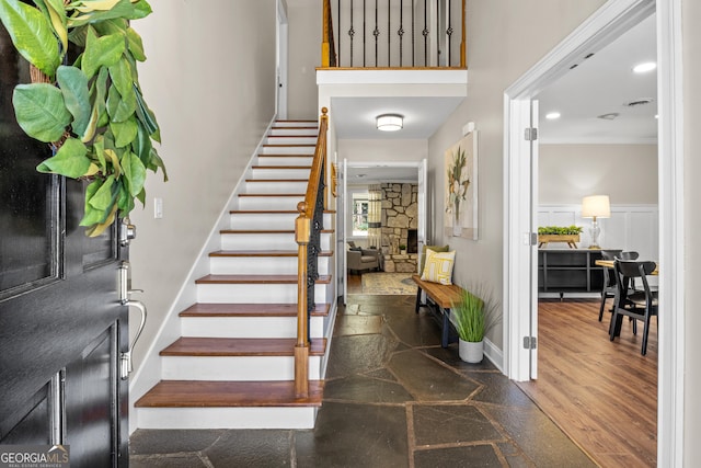 entryway featuring visible vents, stairway, wainscoting, a decorative wall, and crown molding