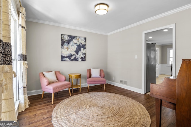 living area featuring visible vents, baseboards, ornamental molding, recessed lighting, and wood finished floors