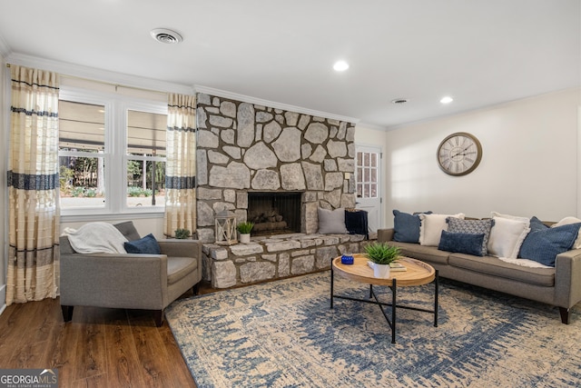 living area featuring visible vents, a healthy amount of sunlight, wood finished floors, and crown molding