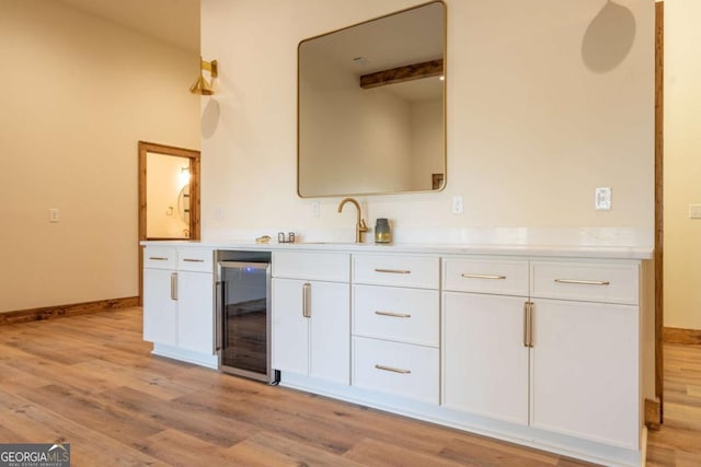 kitchen featuring light wood-style floors, beverage cooler, light countertops, and white cabinetry