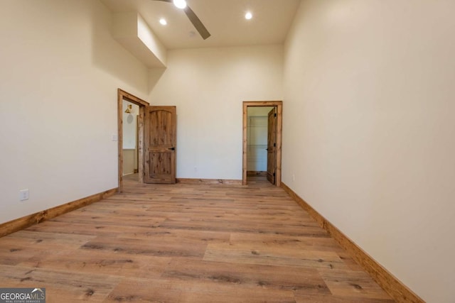 unfurnished room featuring recessed lighting, a high ceiling, baseboards, and wood finished floors