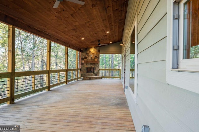 wooden deck with a ceiling fan and an outdoor stone fireplace