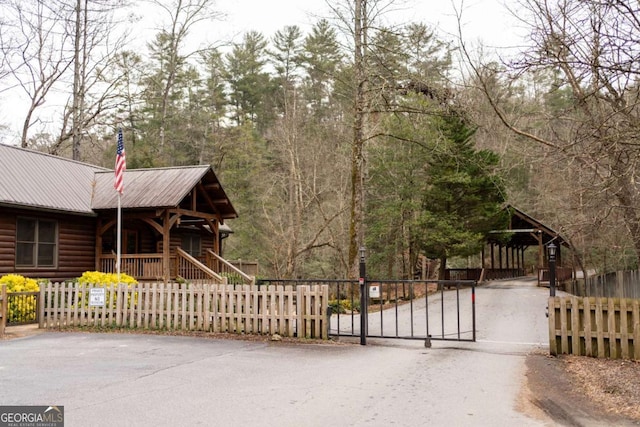 exterior space with a gate, covered porch, a fenced front yard, and metal roof