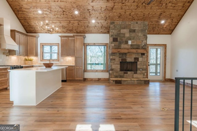 kitchen with custom exhaust hood, backsplash, a fireplace, and light wood-type flooring