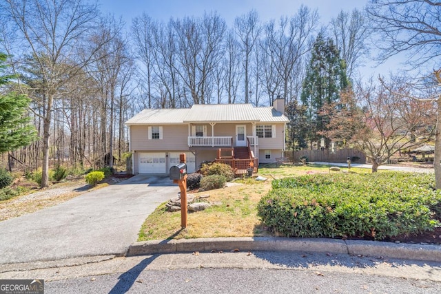 view of front of property with stairs, covered porch, a chimney, metal roof, and a garage