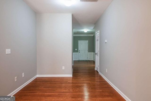 hall featuring visible vents, crown molding, and wood finished floors