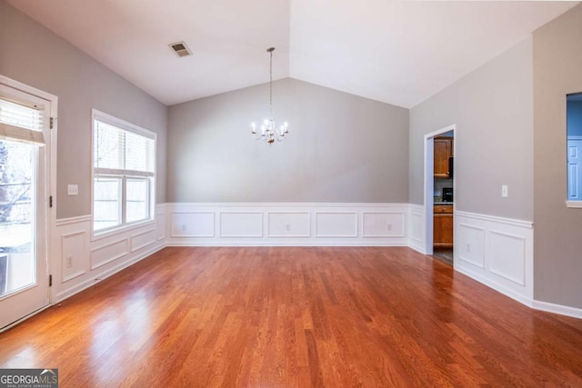 spare room with vaulted ceiling, wood finished floors, visible vents, and a chandelier